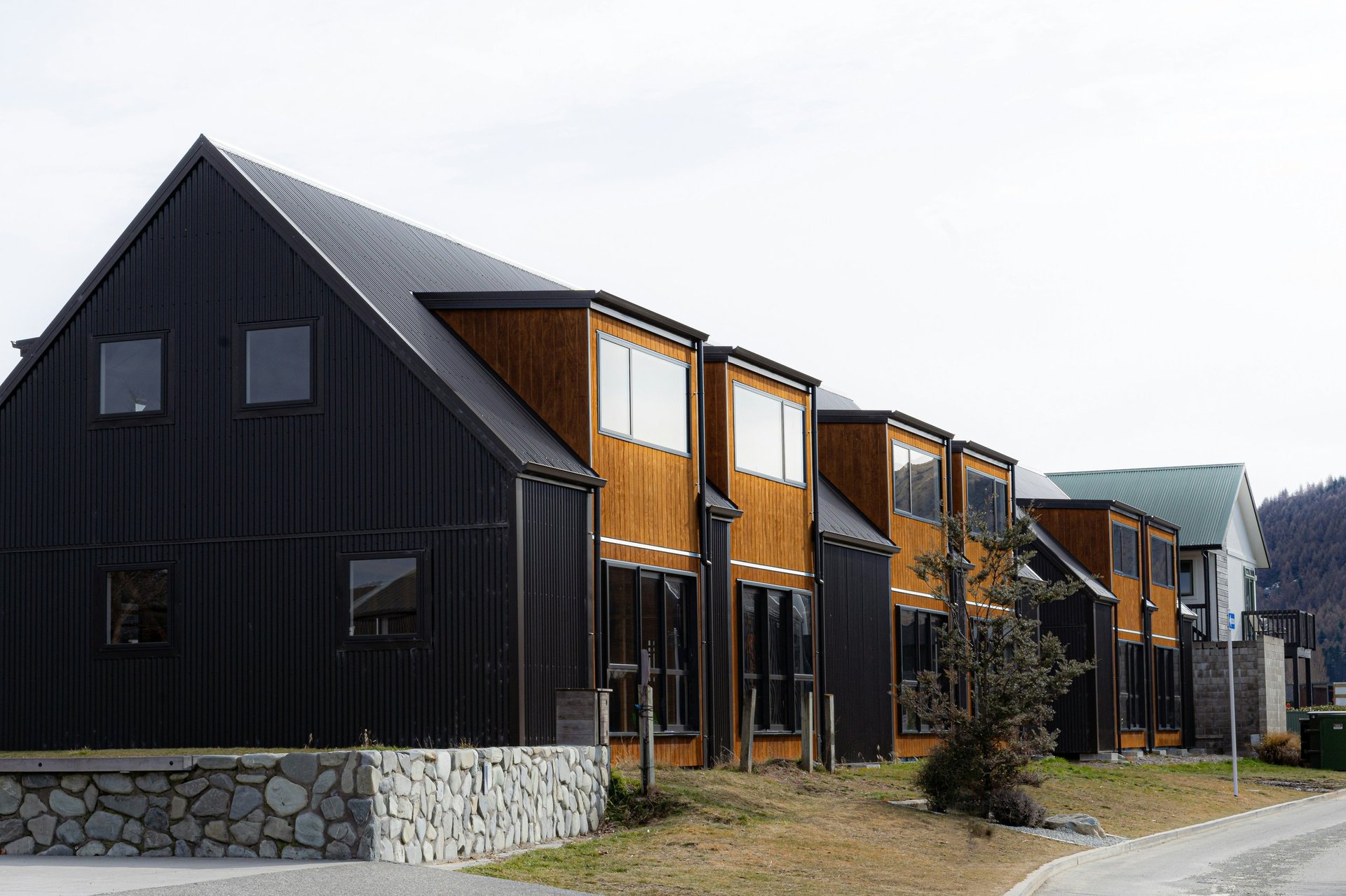 Row of modern black houses with wooden doors and stone foundations in a residential community